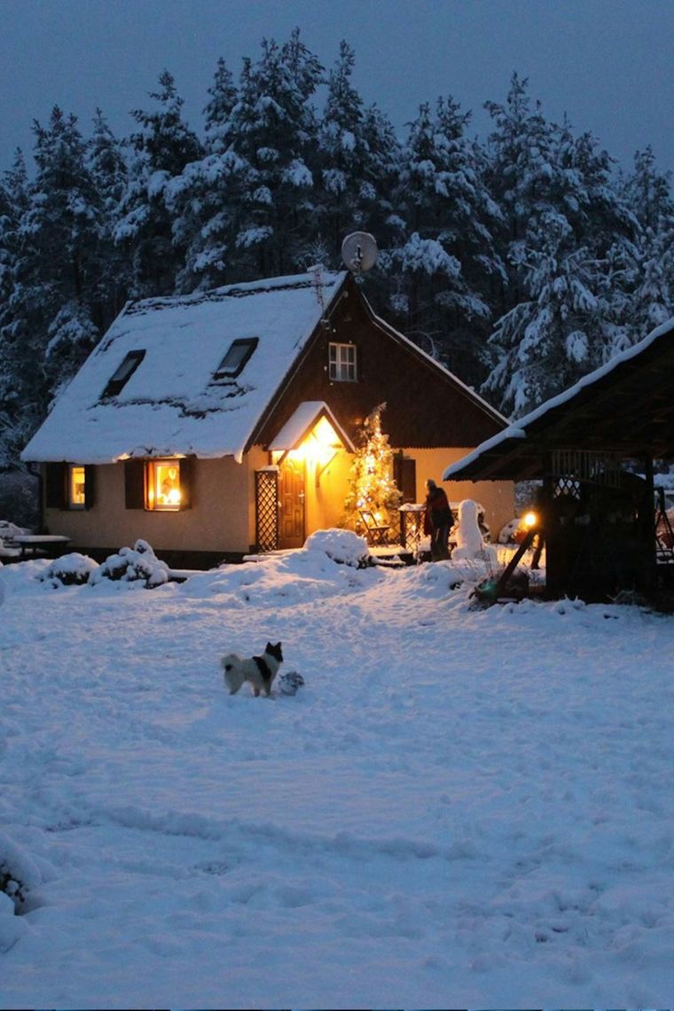 Snow-covered home with warm lights on in winter