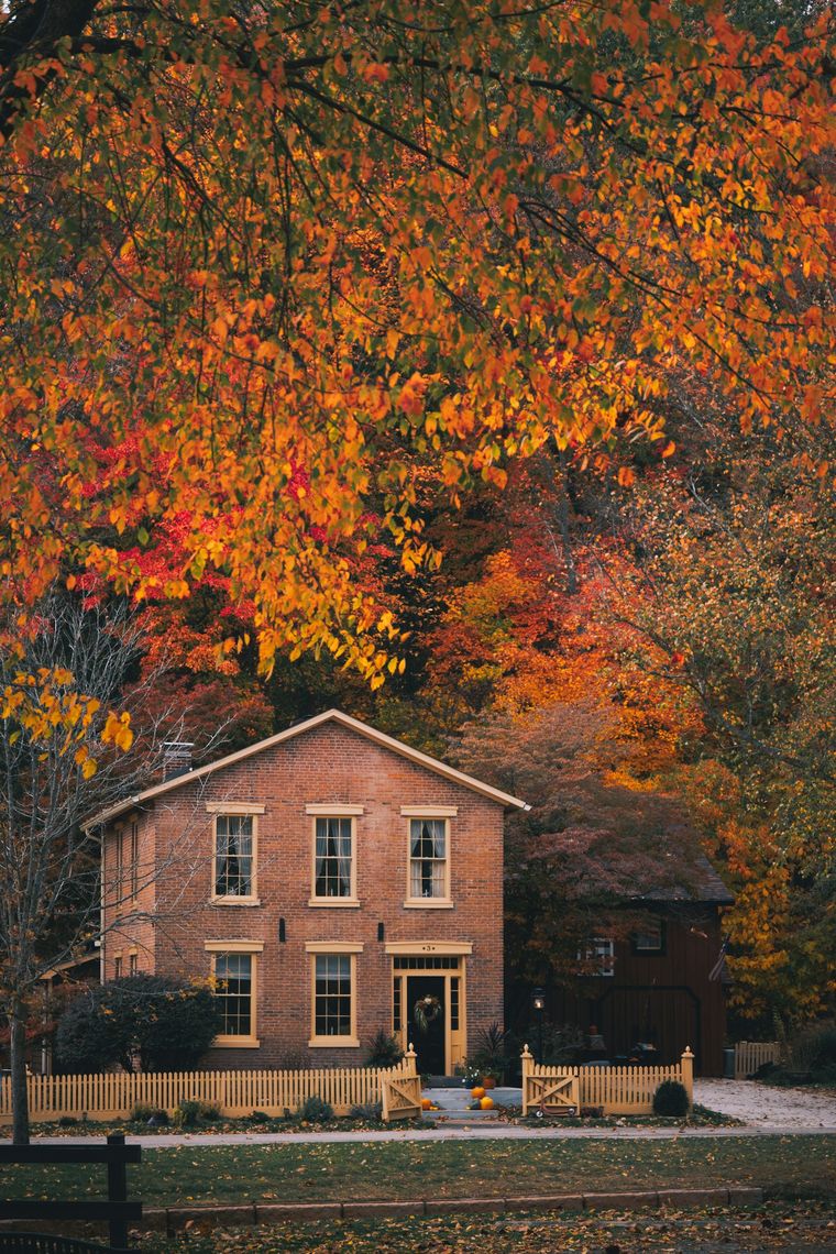 Brick farmhouse surrounded by autumn trees