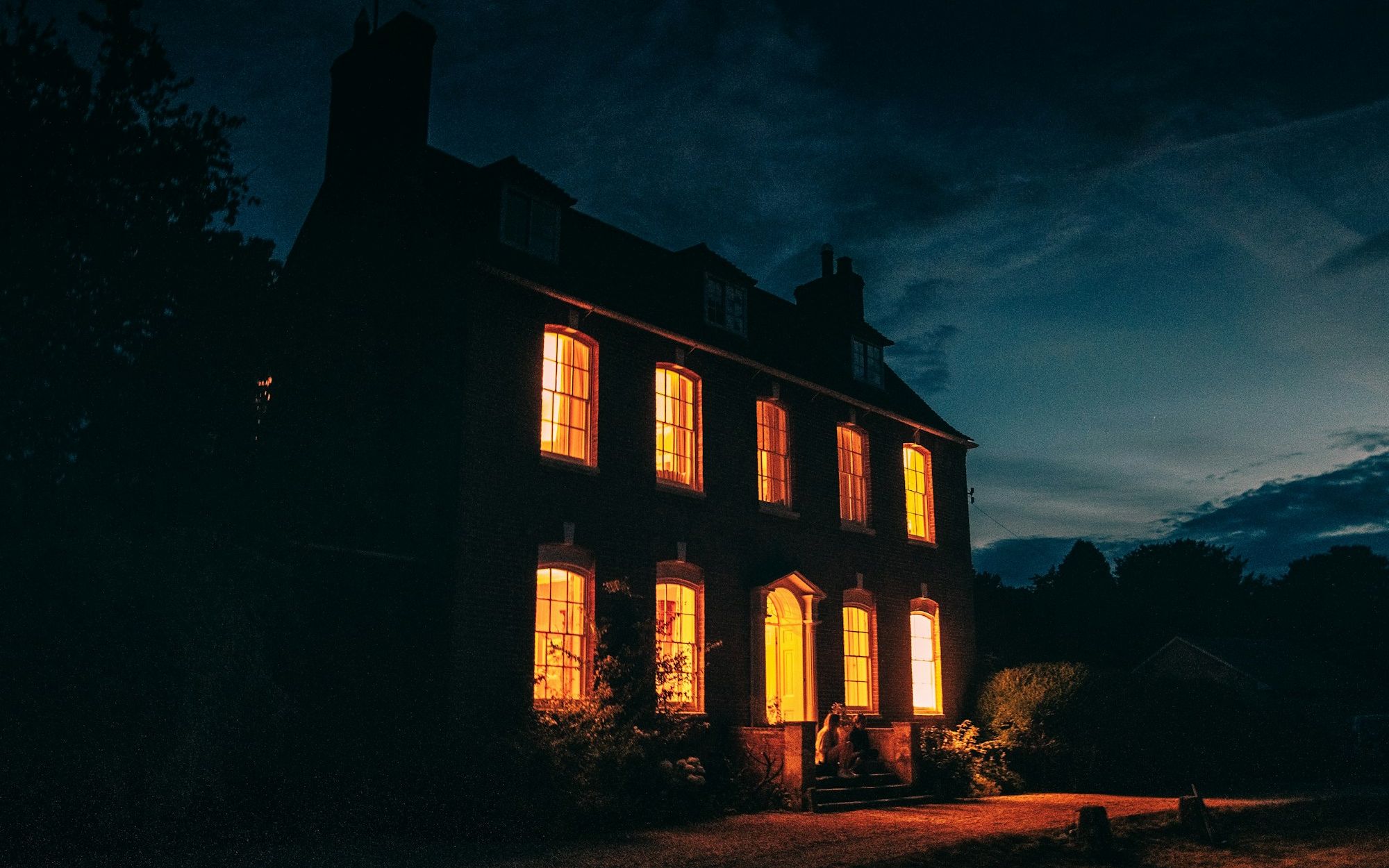 Brick home with warm lights glowing in every window at night