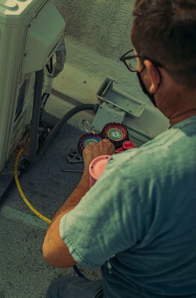 Technician checking refrigerant pressures on an outdoor air conditioner