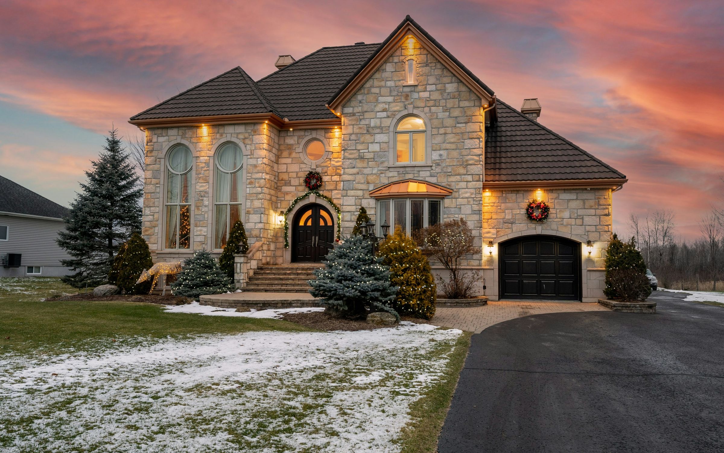 Stone house with warm lights glowing at sunset in early winter