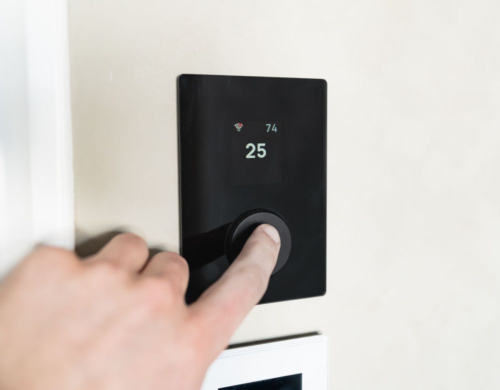 Hand adjusting a modern smart thermostat